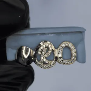 Custom gold open-face grillz featuring a 3D pavé diamond script letter cap and a pavé diamond oval letter cap, shown on a dental mold