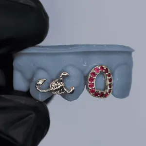 Two custom silver single-tooth caps: a 3D sculpted scorpion cap and an open-face oval cap fully set with ruby pavé stones, shown on a dental mold
