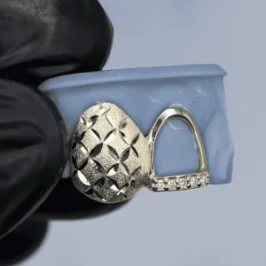 Two custom white gold single-tooth caps shown against a dental mold: one with a diamond-cut textured surface, one open-face with pavé diamond dust detailing