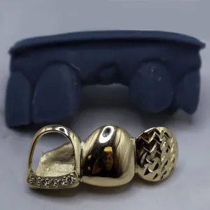Custom gold 3-tooth bottom grillz on a dental cast with missing teeth: one open-face cap, one solid cap, and one diamond-cut textured cap